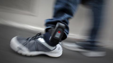Ein Bewährungshelfer demonstriert ein Modell einer elektronischen Fußfessel