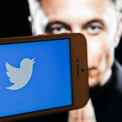 Handy mit Twitter-Symbol, Elon Musk im Hintergrund