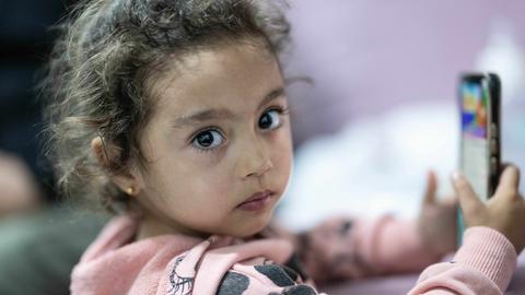 Die kleine  Fatma Nur spielt im Wohncontainer ihrer Familie mit einem Handy. Das Mädchen war bei dem Erdbeben im Jahr 2023 unter den Trümmern eines Hauses verschüttet worden und konnte erst nach 56 Stunden gerettet werden. 