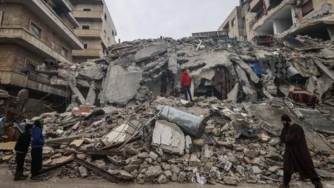 Menschen betrachten die Trümmer eines zerstörten Wohnhauses in Idlib, Syrien. 
