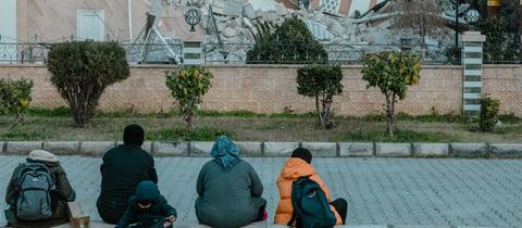 Eine Familie sitzt vor der eingestürzten Moschee in Iskenderun