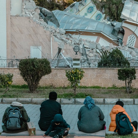 Eine Familie sitzt vor der eingestürzten Moschee in Iskenderun