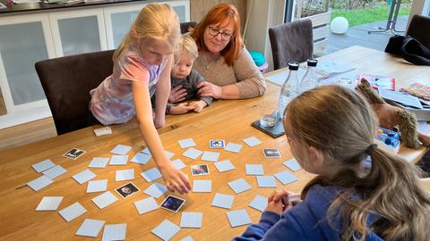 Elke Groß sitzt mit den drei Kindern am Tisch, sie spielen gemeinsam Memory.