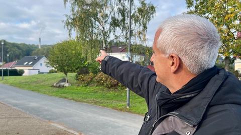 Mann zeigt auf Schornstein im Wald