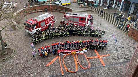 Feuerwehrleute in Bebra, mehrere Feuerwehrautos und eine große 100 aus ausgebreiteten Schläuchen 