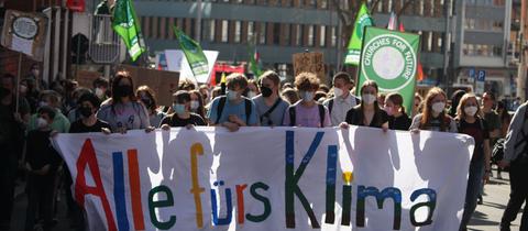 Eine Gruppe Menschen läuft durch Kassel, sie tragen ein Banner mit der Aufschrift "Alle fürs Klima"