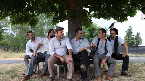 Gruppe von Männern sitzt um einen Baum 