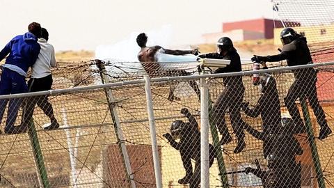 Spanische Polizisten gehen mit einem Feuerlöscher gegen einen Mann vor, der die Grenze zwischen Marokko und der spanischen Enklave Melilla überqueren wollte.
