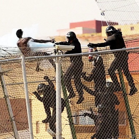 Spanische Polizisten gehen mit einem Feuerlöscher gegen einen Mann vor, der die Grenze zwischen Marokko und der spanischen Enklave Melilla überqueren wollte.