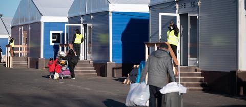 Menschen mit Türen vor Container-Häusern