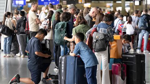 Wartende stehen am Flughafen Schlange.