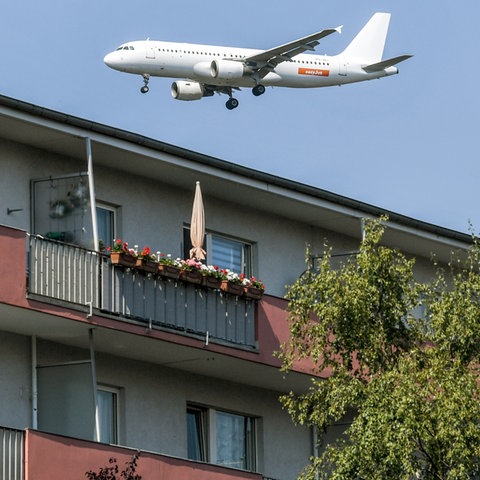 Ein Flugzeug überfliegt beim Landeanflug Wohnhäuser