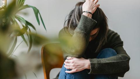 Eine Frau sitzt auf einem Sessel und rauft sich die Haare