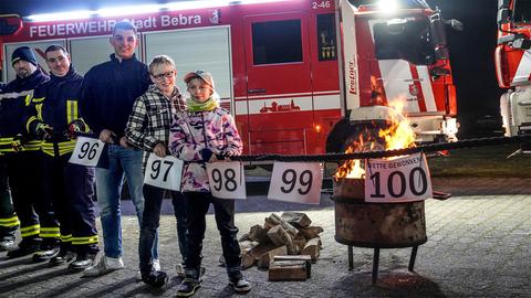 Mehrere Menschen stehen vor einem Feuerwehrfahrzeug und halten Nummern in der Hand