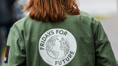 Eine Demonstrantin trägt eine Jacke mit dem Fridays-for-Future-Logo auf dem Rücken.