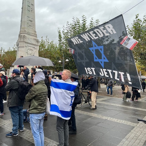 Menschen mit Regenschirmen, Bannern, Plakaten und Israelflaggen.