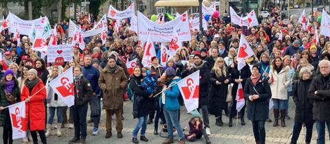 Viele Menschen stehen vor der Alten Oper in Frankfurt und halten Fahnen in die Höhe.