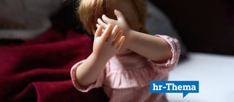 Sujetfoto: Eine Puppe, welche die Hände vor ihr Gesicht hält, um Schläge abzuwehren.