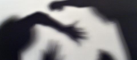 Schatten einer Person, die von zwei anderen geschlagen wird.