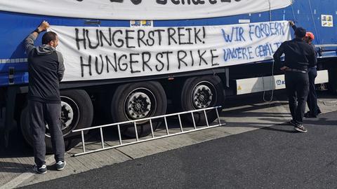 Zwei Männer hängen ein Banner mit der Aufschrift "Hungerstreik" an einem Lkw auf.