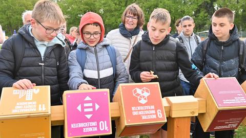 Schüler aus Hofbieber drehen Würfel mit Fragen und Antworten im Grünen Klassenzimmer bei der Landesgartenschau, im Hintergrund Umweltministerin Priska Hinz