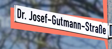 Straßenschild mit der Beschriftung "Dr. Josef-Gutmann-Straße". Hinter dem Straßenschild liegt eine farbige Fläche, dahinter unscharf leicht verfärbt Strukturen eines Baumes.