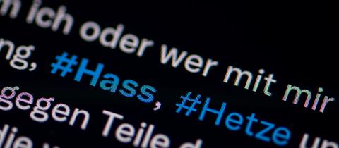 Der Bildschirm eines Smartphones zeigt die Hashtags #Hass" und #Hetze in einem Tweet.