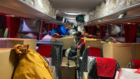 Innensicht eines Reisebusses, in dem sich Kisten mit Hilfsgütern stapeln.