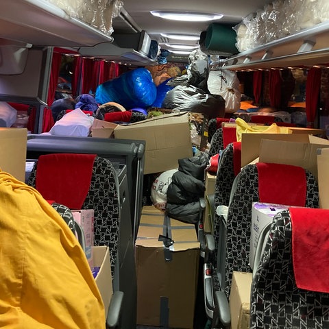 Innensicht eines Reisebusses, in dem sich Kisten mit Hilfsgütern stapeln.