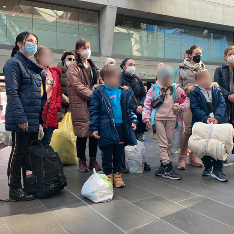 Eine Gruppe von Menschen mit Gepäck steht in einer Halle.