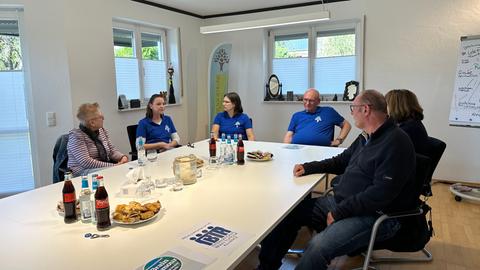 Sechs Männer und Frauen sitzen im Gruppenraum der Hirntumor-Selbsthilfegruppe Mittelhessen um einen Tisch herum.