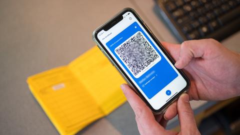 Gelber Impfpass und ein Smartphone mit QR-Code