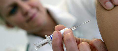 Großaufnahme: Eine Impfspritze wird in einen Oberarm gestochen.