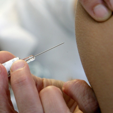 Großaufnahme: Eine Impfspritze wird in einen Oberarm gestochen.
