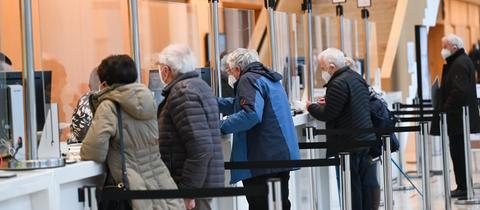 Impfpatienten stehen im Wiesbadener Impfzentrum im Kongresszentrum RMCC an den Registrierungsschaltern.