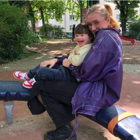 Inkluencerin Fredi mit ihrem Sohn Lion auf einem Spielplatz, beide lachen in die Kamera