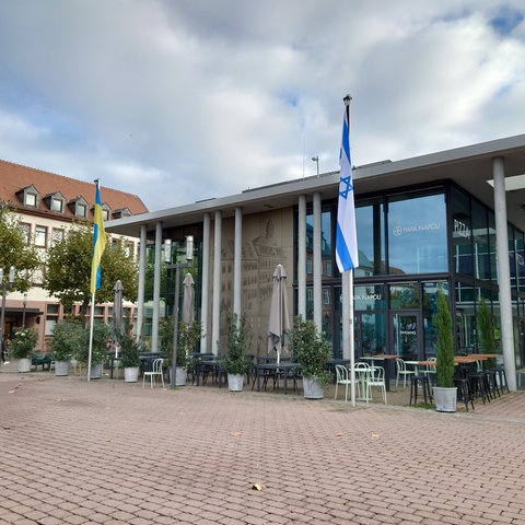 Israel-Flagge an Fahnenmast neben weiterem Fahnenmast mit Ukraine-Flagge.