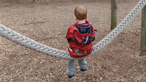 Kind von hinten fotografiert alleine auf dem Spielplatz