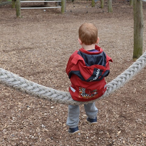 Kind von hinten fotografiert alleine auf dem Spielplatz