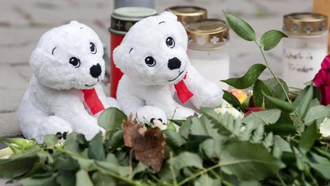 Zwei Plüsch-Eisbären, Blumen und Grabkerzen in Großaufnahme.