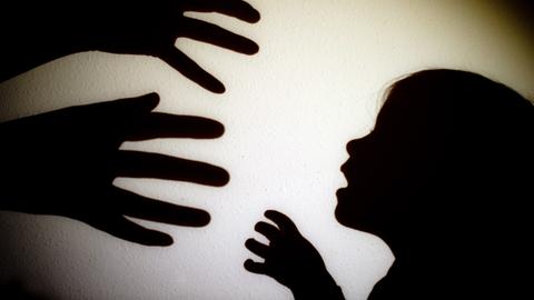 Fotografischer Schattenriss: Zwei Hände greifen nach einem Kind