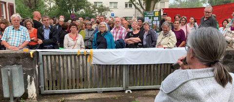 Frau, von hinten zu sehen, spricht zu einer Menschenmenge