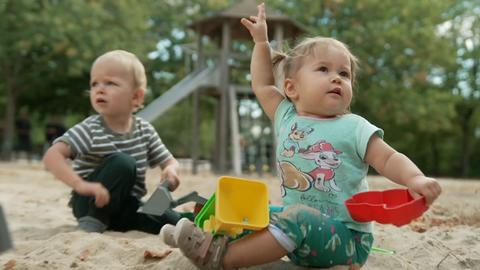 Zwei Kinder sitzen im Sand und spielen.