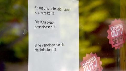 Ein Zettel klebt an einer Glastür. Auf ihm steht: "Es tut uns leid, diese Kita streikt!!! Die Kita bleibt geschlossen!!! Bitte verfolgen Sie die Nachrichten"