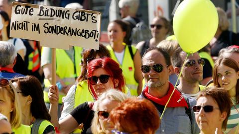 Menschenmasse mit Frauen und Männern mit gelben Westen. Eine Frau hält ein Schild mit dem Text "Gute Bildung gibt es nicht im Sonderangebot". 