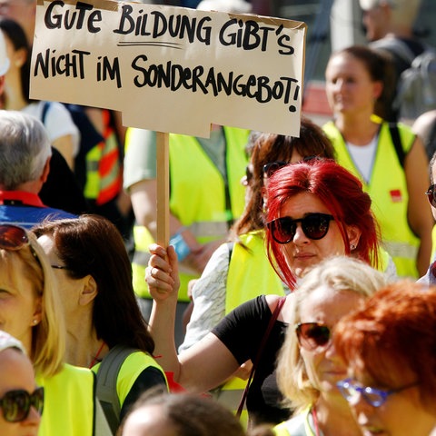 Menschenmasse mit Frauen und Männern mit gelben Westen. Eine Frau hält ein Schild mit dem Text "Gute Bildung gibt es nicht im Sonderangebot". 