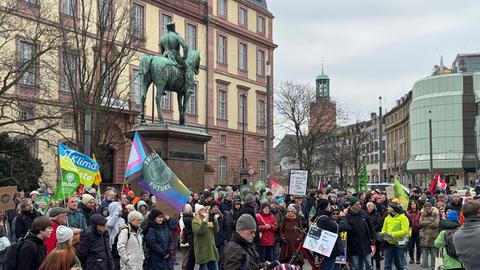 Menschen stehen auf dem Marktplatz in Darmstadt mit Plakaten.