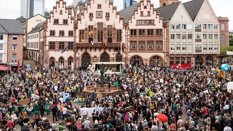 Eine Menschenmenge, teilweise mit Plakaten und Fahnen in den Händen, befindet sich vor dem Frankfurter Rathaus