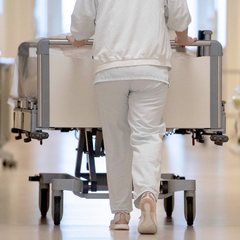Pfleger schiebt ein Bett über einen Krankenhausflur