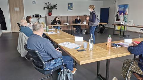 Eine Dozentin spricht im Seminarraum mit Teilnehmern des Krisenhelfer-Kurses.